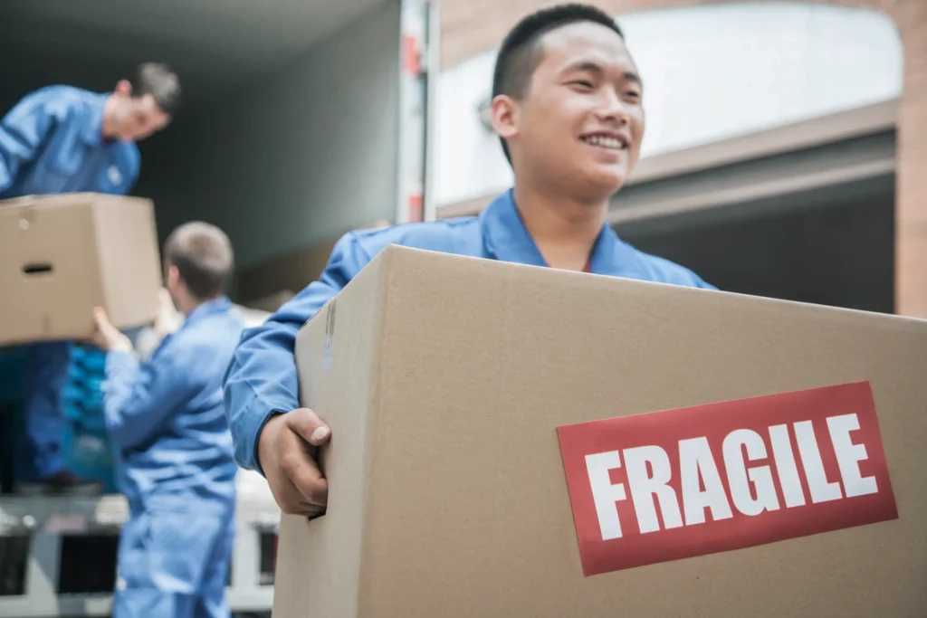 Movers carefully handling a box labeled 'FRAGILE', exemplifying seamless moving services