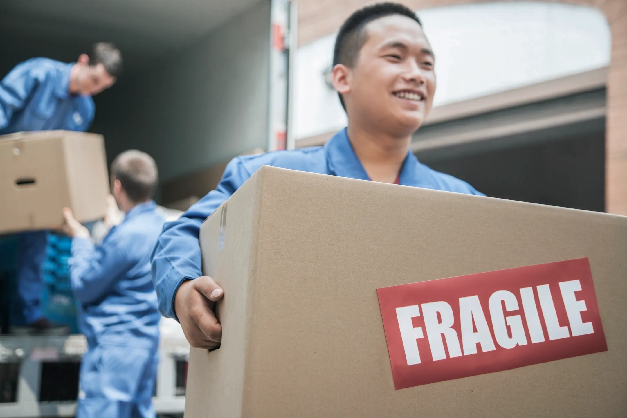 Movers carefully handling a box labeled 'FRAGILE', exemplifying seamless moving services