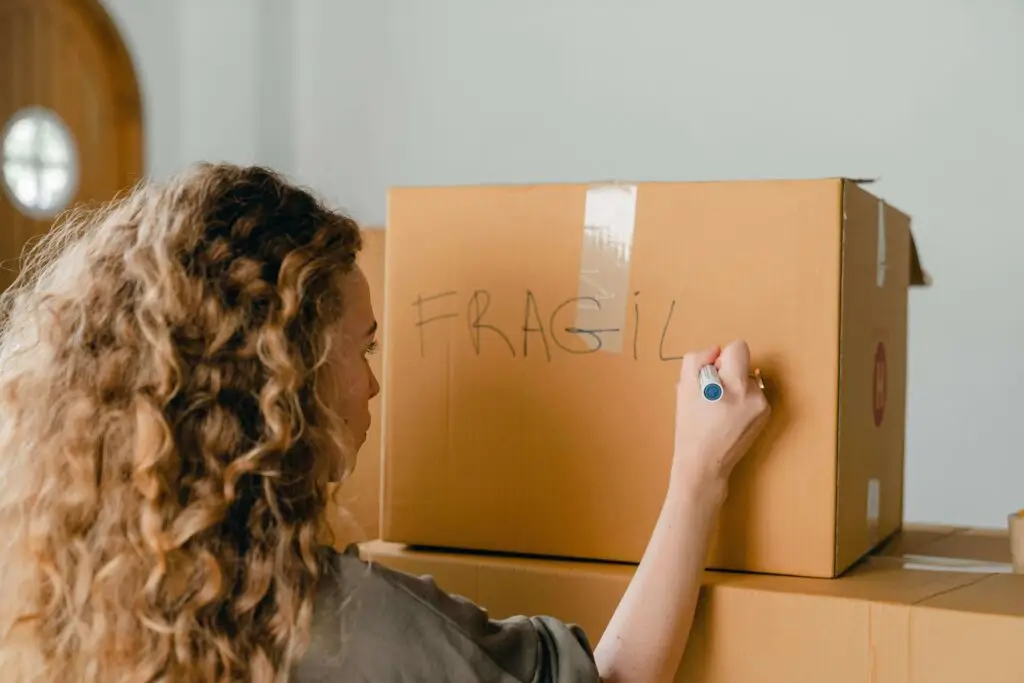 Customer marking a cardboard box as fragile while preparing for a move in Sydney.