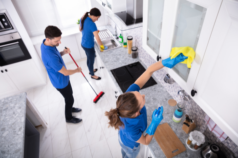 Team of professional cleaners performing deep cleaning in a modern kitchen.