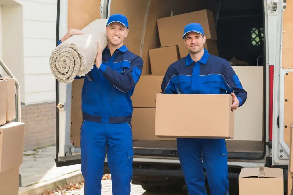 Removal crew with a rolled-up carpet and boxes ready to load into a moving van in Sydney.