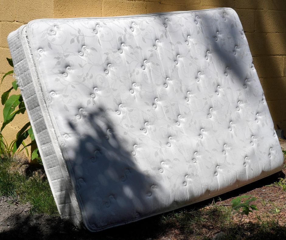 Old mattress leaning against a wall, highlighting the need for mattress removal services.