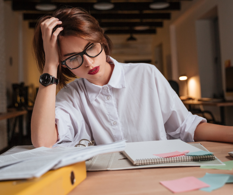 Stressed woman working at her desk with documents and notebooks, representing the need for affordable and reliable removalists nearby